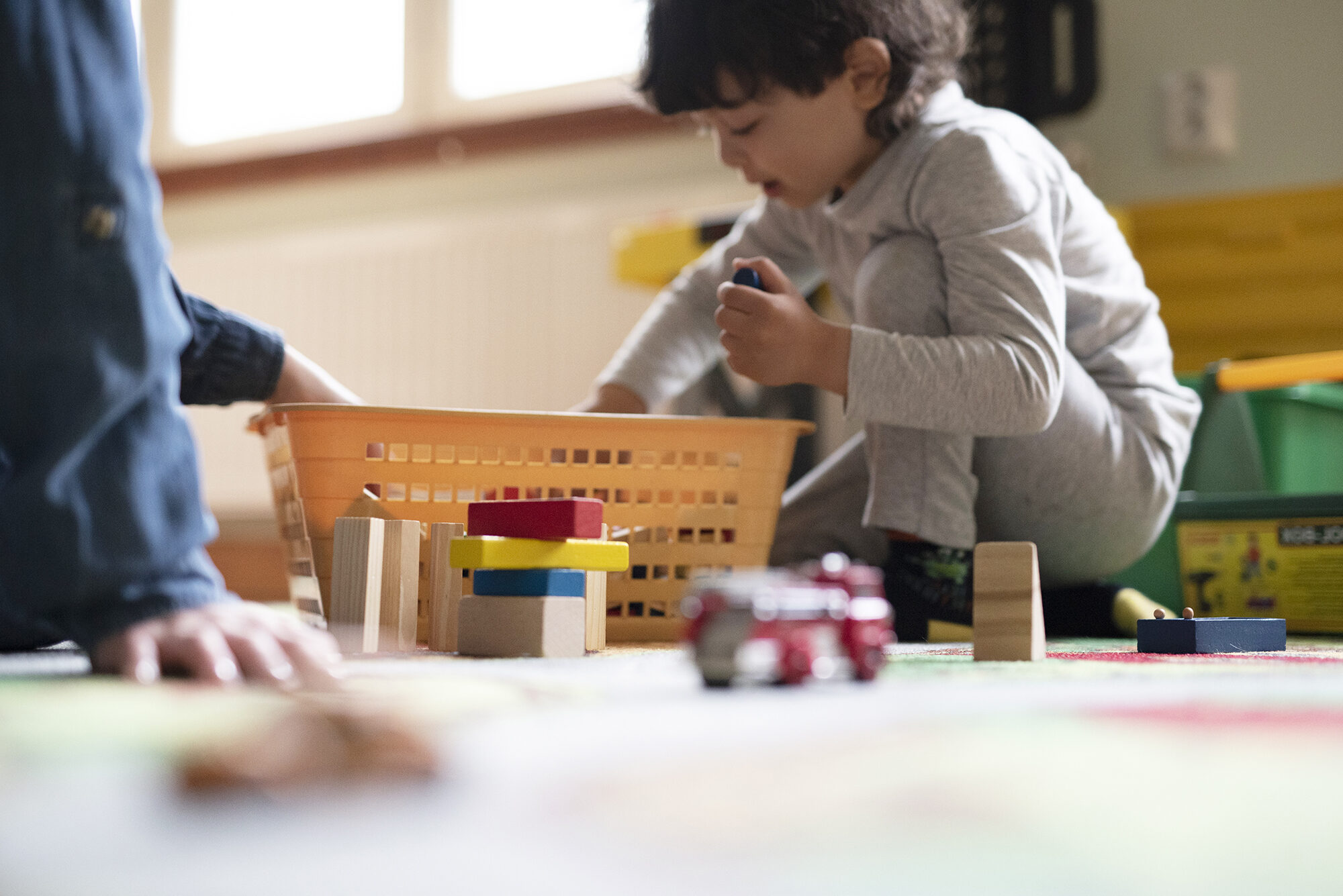 Lapsi leikkii lattialla palikoilla.